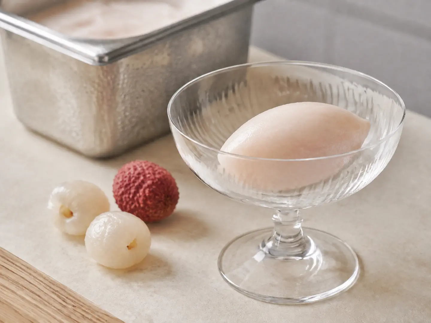 Une quenelle de sorbet au litchi, blanc rosé, dans une coupe en verre.